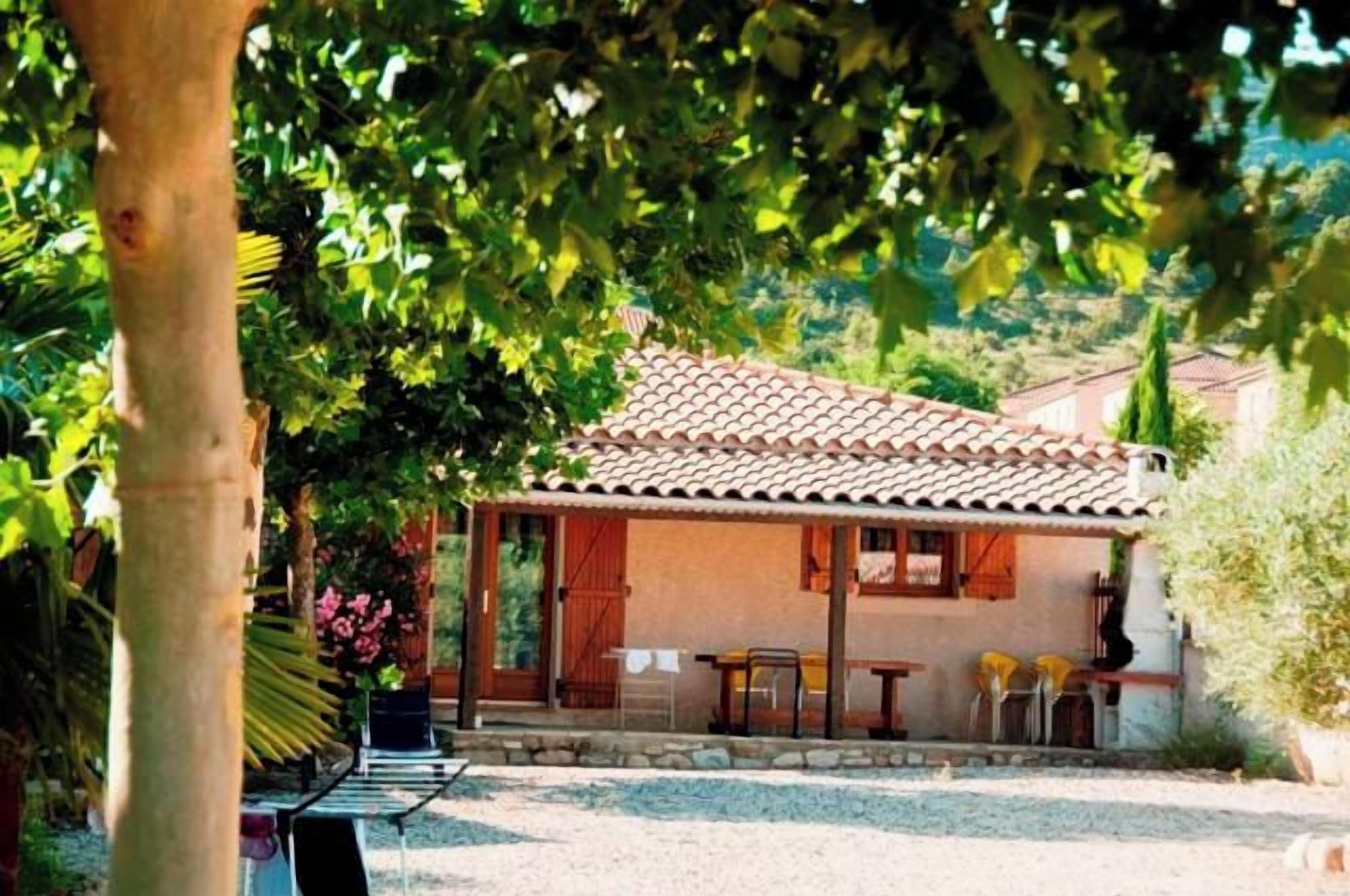 A house with a tiled roof, a covered patio, and a gravel driveway.