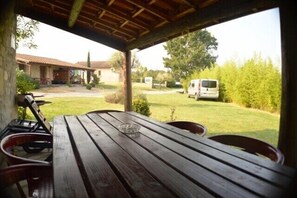 Ein Tisch aus Holz mit Stühlen im Freien, mit Blick auf eine Wiese, und ein weißer Transporter im Hintergrund.