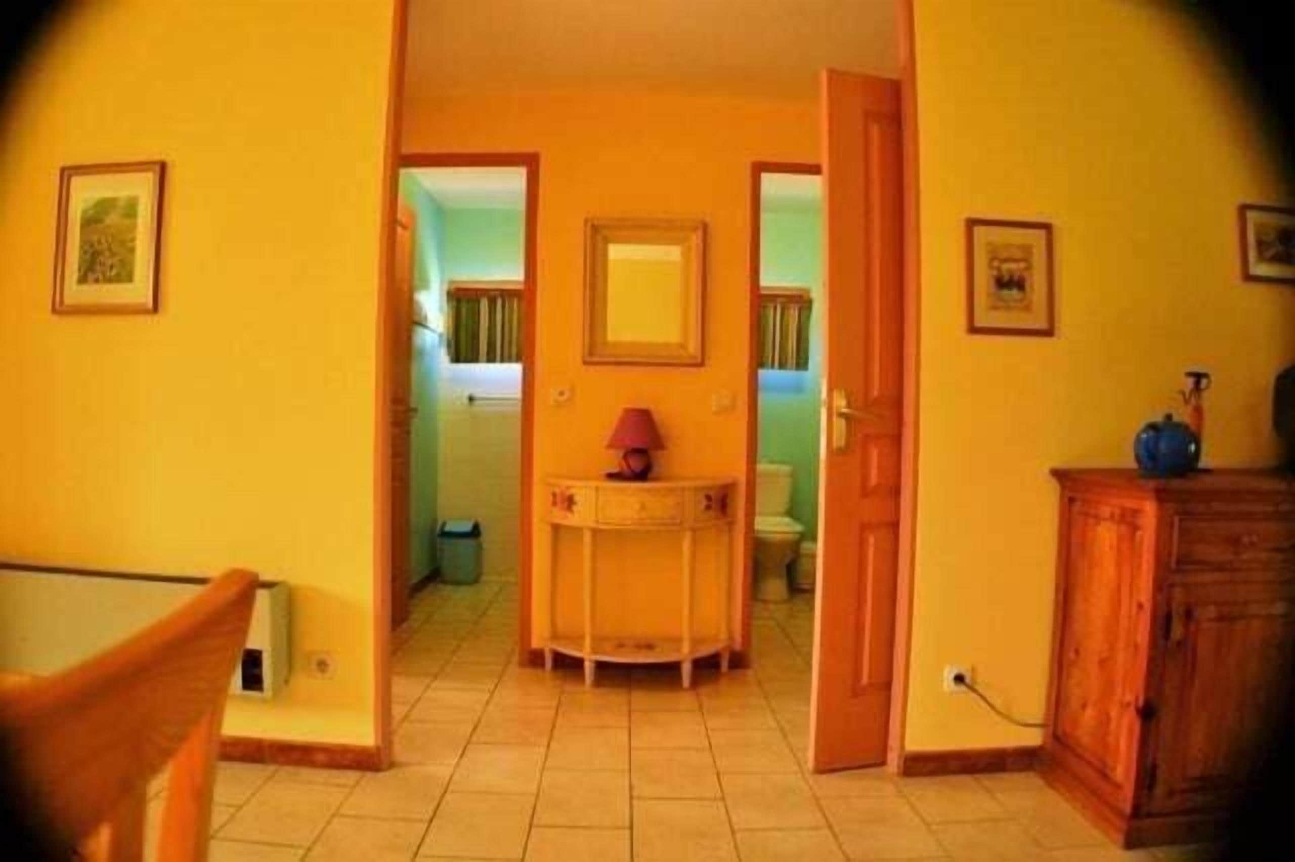 Un couloir avec une porte donnant sur une salle de bain, une petite table avec une lampe et un meuble.