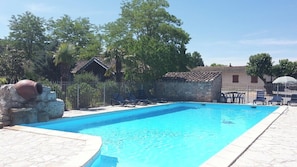 Ein Pool mit Liegestühlen und einer Steinmauer.