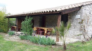 A rustic stone building with a tiled roof, a covered porch with wooden furniture, and a sign indicating 'PULLEPSTRAAT.' - Mirabel #4, Small House, Terrace, and Pool Access (Grospierres)