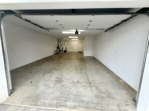 Eine Garage mit Betonboden, weißen Wänden und einer Tür zu einem Flur.