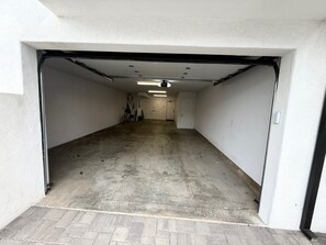Eine Garage mit Betonboden, weißen Wänden und einer Tür zu einem Flur.