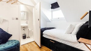 Un dormitorio con cama, mesita de noche, lámpara colgante, ventana y armario.