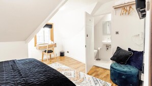 Un dormitorio con cama, escritorio y baño con lavamanos y espejo.
