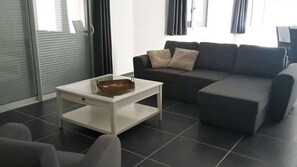 Ein Wohnzimmer mit einer Couch, einem Couchtisch und einer Schiebetür aus Glas.