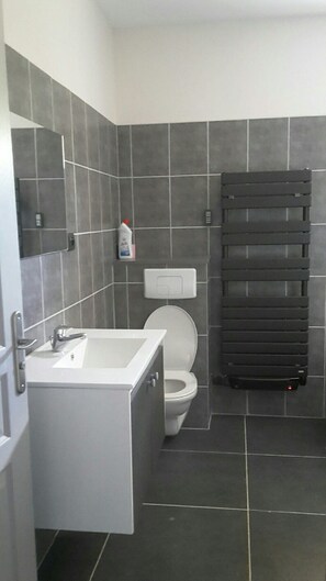 Un baño con un lavamanos blanco, un inodoro y un perchero para toallas.
