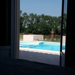 Vista de una piscina con cielo despejado y árboles al fondo.