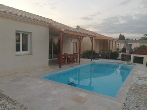 A swimming pool with a pergola and outdoor seating, surrounded by a patio area. - "Chez Nous" Villa, with Air Conditioning, Pool, BBQ, and Terrace (Grospierres)
