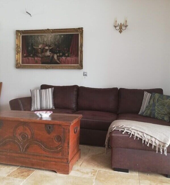 Un salon avec un canapé, une table basse en bois et un tableau encadré accroché au mur.