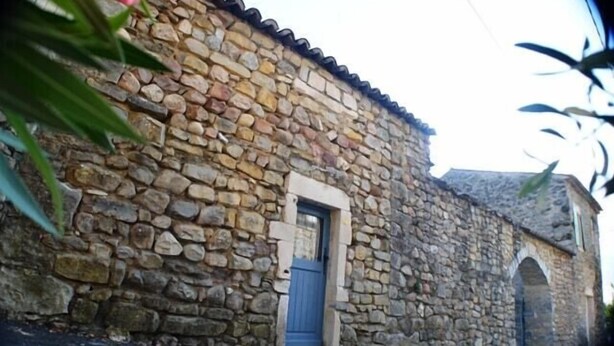 A stone building with a blue door and an arched entrance. - Vrbo Property (Grospierres)