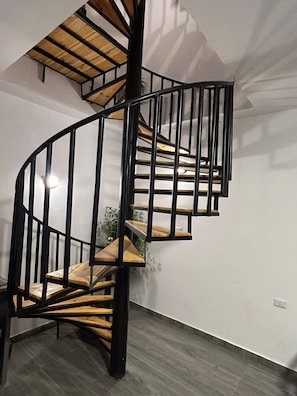 Una escalera de caracol con peldaños de madera y barandillas de metal negro.