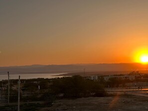 Un atardecer sobre un paisaje costero con edificios y una carretera.