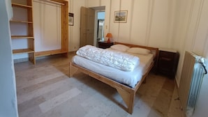 A bedroom with a wooden bed, a wardrobe, and a radiator. - Vrbo Property (Grospierres)