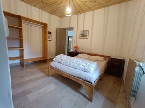 Ein Schlafzimmer mit einem hölzernen Bett, einem Kleiderschrank und einer Heizung.