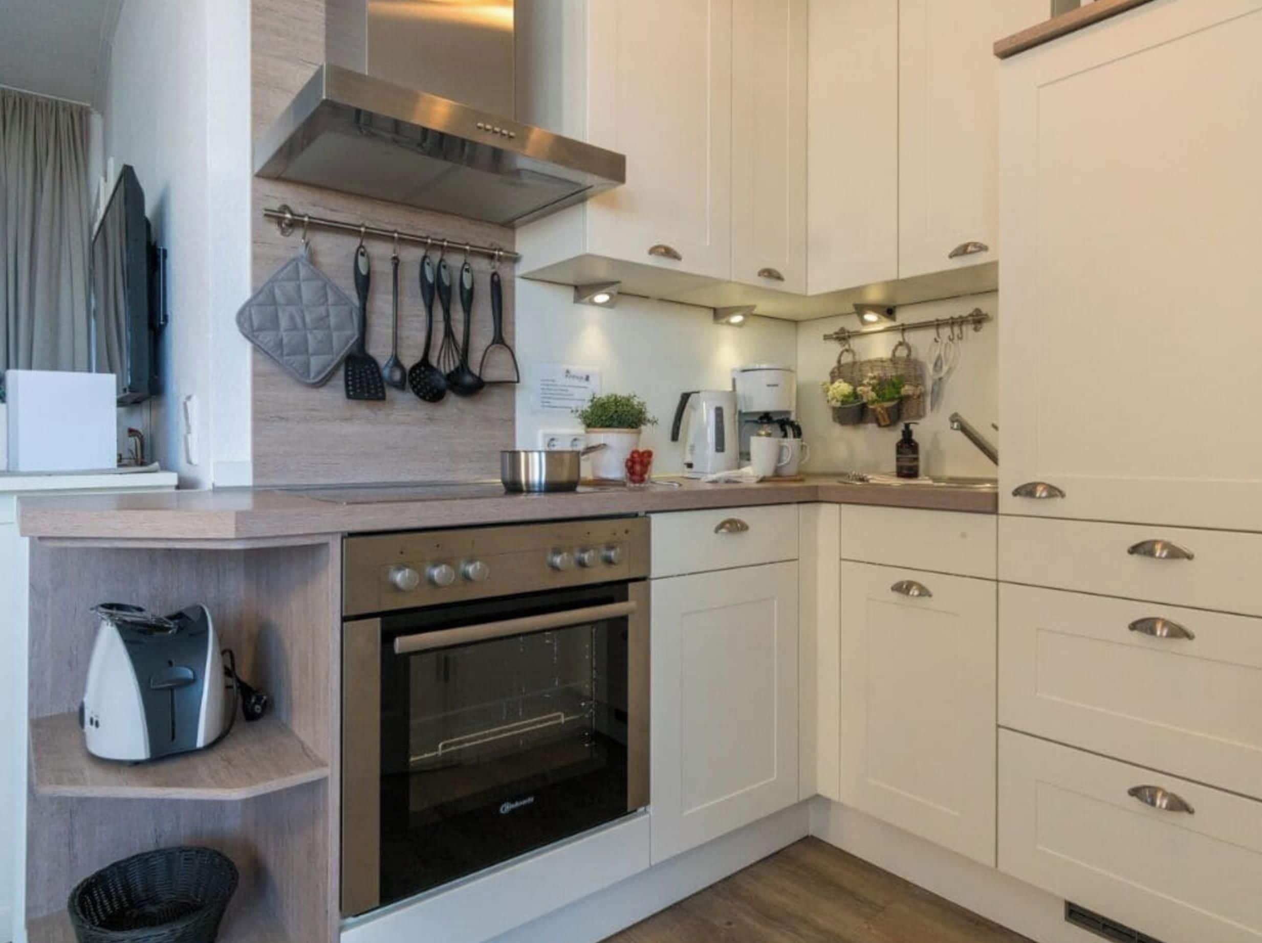Een moderne keuken met witte kasten, een roestvrijstalen afzuigkap en een inbouwoven.