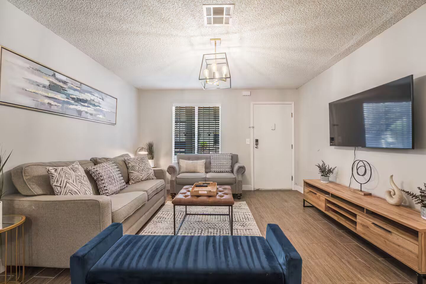 Een woonkamer met een bank, een salontafel, een televisie en een houten dressoir.