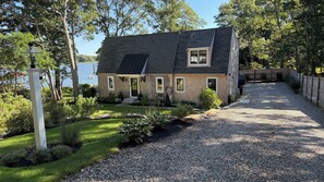 A house with a gravel driveway, a lawn, and a view of a lake. - Summersea 3-bedroom house on the water in soothing New Seabury, Mashpee (Mashpee)