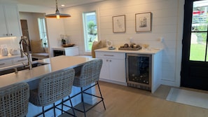 A modern kitchen with a central island, bar stools, pendant lighting, and a view of the outdoors. - Summersea 3-bedroom house on the water in soothing New Seabury, Mashpee (Mashpee)