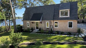 Een twee verdiepingen tellend huis met een schuin dak, een veranda en uitzicht op een meer.