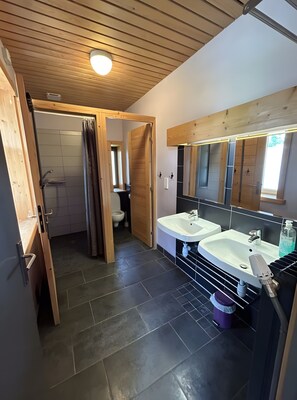 Ein Badezimmer mit zwei Waschbecken, einer Dusche und einer Toilette.