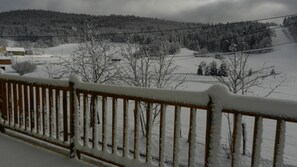 A snowy landscape with a wooden fence in the foreground.