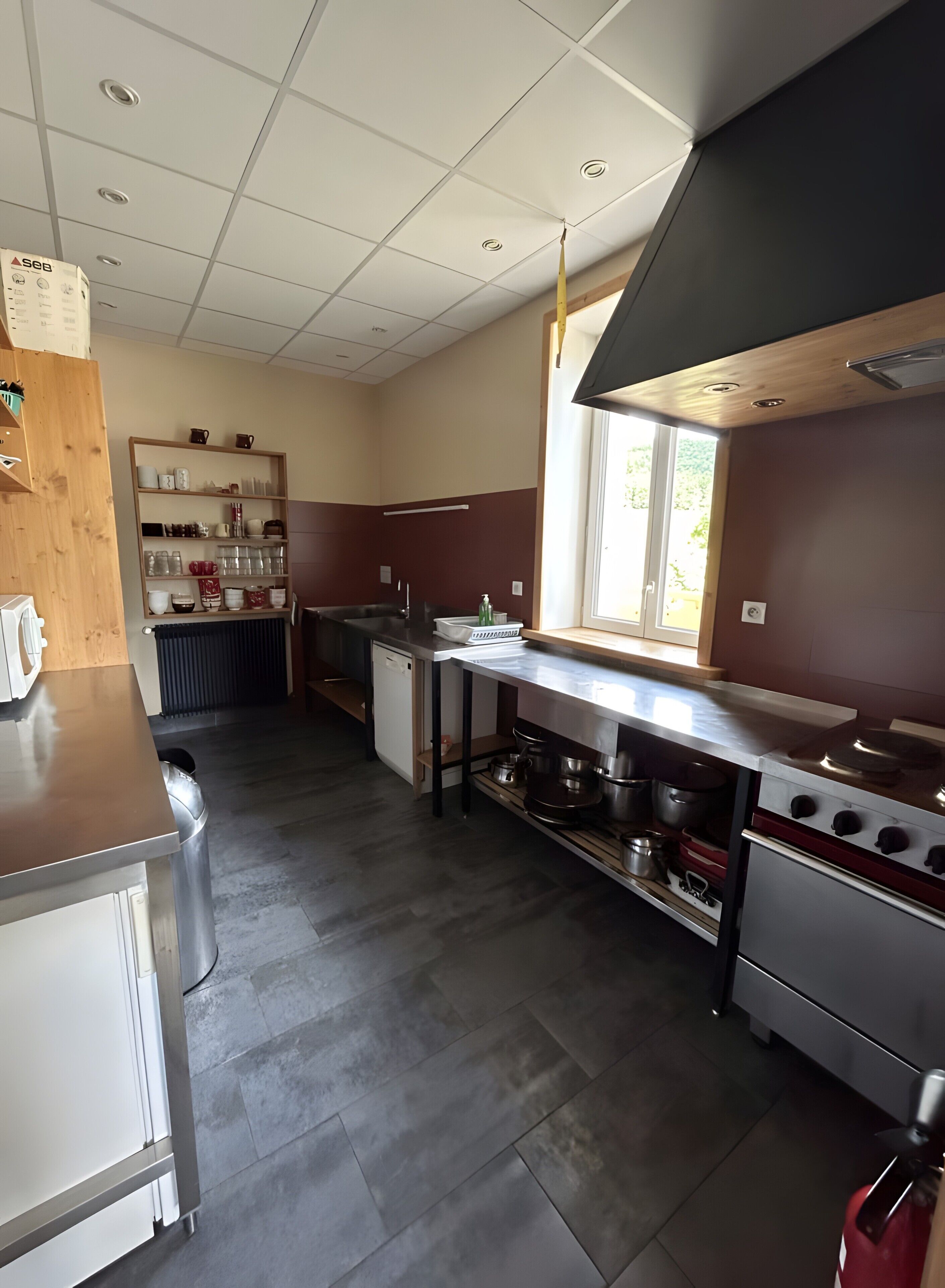 A kitchen with a stainless steel countertop, a built-in oven, and a window providing natural light.