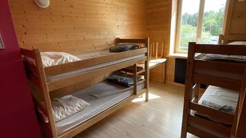 A room with wooden bunk beds, a window with a view, and a ceiling fan.