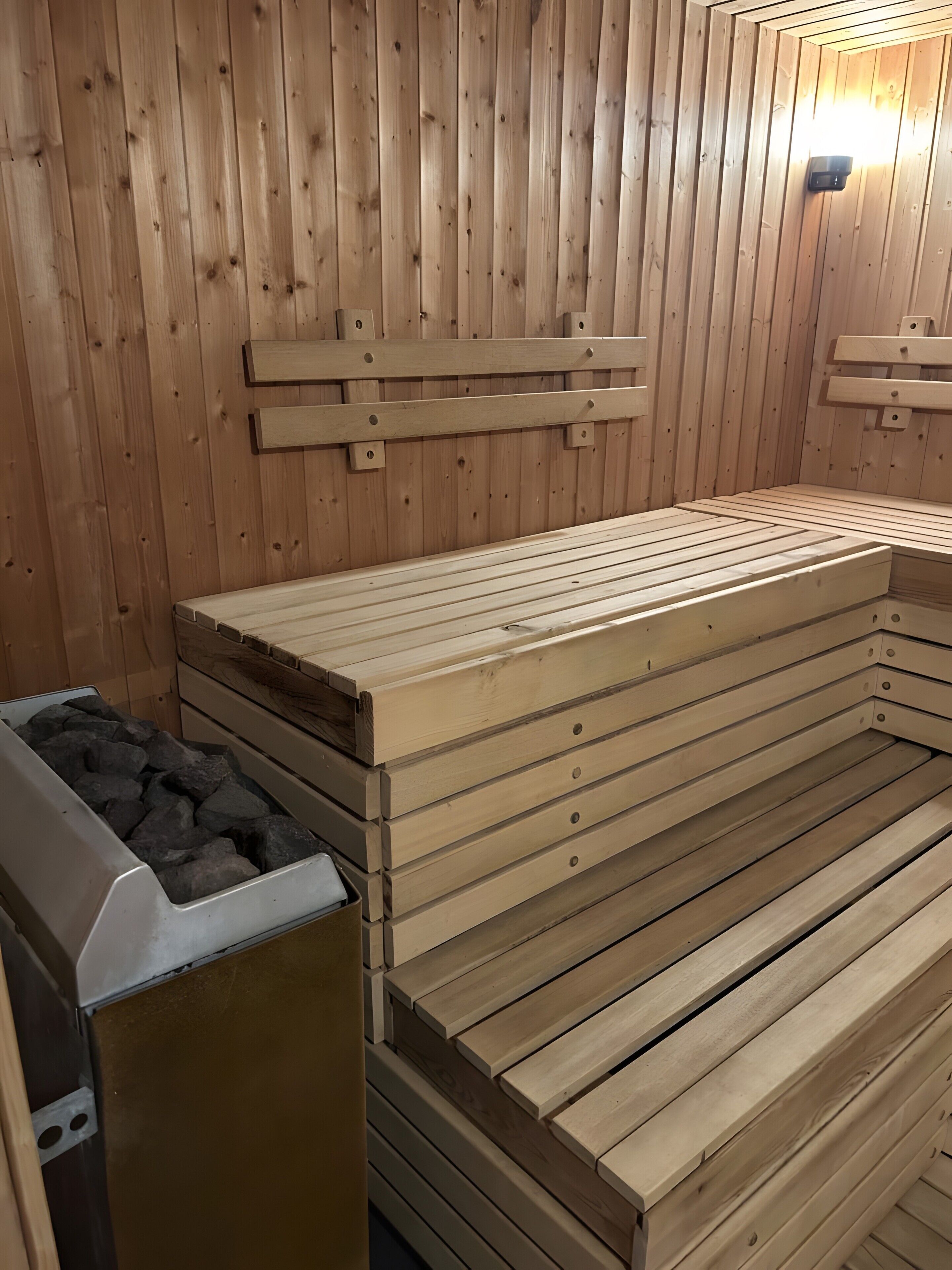A sauna with wooden benches and a stone-filled container, likely for hot stones.