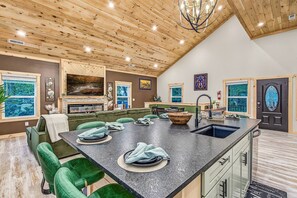 A modern kitchen with a large island, green upholstered seating, and a fireplace. - A+ in Chalet Village just 1.5 miles to Great Smoky Mountains #HotTub #Theatre (Gatlinburg)