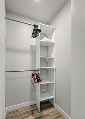 A white closet with open shelves and hanging space, featuring a wooden floor. - Blazing Elephant - Stunning VIEWS, Pet Friendly, Central Location (Sedona)