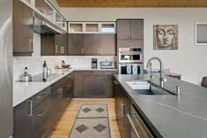 A modern kitchen with dark wood cabinets, a stainless steel sink, and a built-in oven. - Blazing Elephant - Stunning VIEWS, Pet Friendly, Central Location (Sedona)