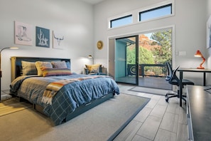 Quarto com cama, escrivaninha e vista para o exterior.