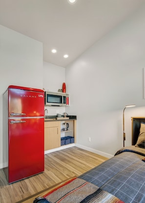 A compact kitchen with a red refrigerator, microwave, and wooden cabinets. - Blazing Elephant - Stunning VIEWS, Pet Friendly, Central Location (Sedona)