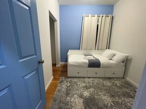 A bedroom with a bed, a door, and a window with curtains. - 3-bed/2-bath apt in Jersey City mins from NYC/American Dream/Jets & Giants Arena (Jersey City)