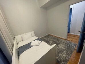 A bedroom with a bed, a gray rug, and a door leading to another room. - 3-bed/2-bath apt in Jersey City mins from NYC/American Dream/Jets & Giants Arena (Jersey City)