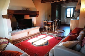 Ein Wohnzimmer mit Kamin, Fernseher, Essbereich und einer Couch.