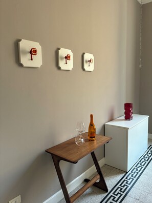 Une pièce avec une table en bois, un verre à vin, une bouteille et trois interrupteurs fixés au mur.