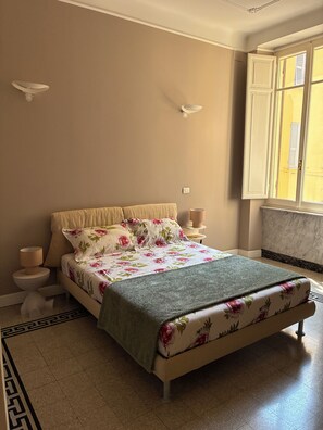 A bedroom with a bed, bedside tables, a window, and a decorative wall light. - Rattazzi 36 - La Spezia & 5 Terre (ITALIA)