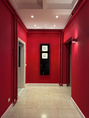 A hallway with red walls, a tiled floor, and recessed ceiling lights. - Rattazzi 36 - La Spezia & 5 Terre (ITALIA)