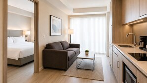 Ein modernes Hotelzimmer mit Bett, Sofa, Couchtisch und Küchenzeile.