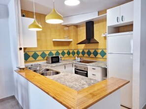 A kitchen with a wooden countertop, a microwave, a sink, and a stove. - Catalina C (Turre)