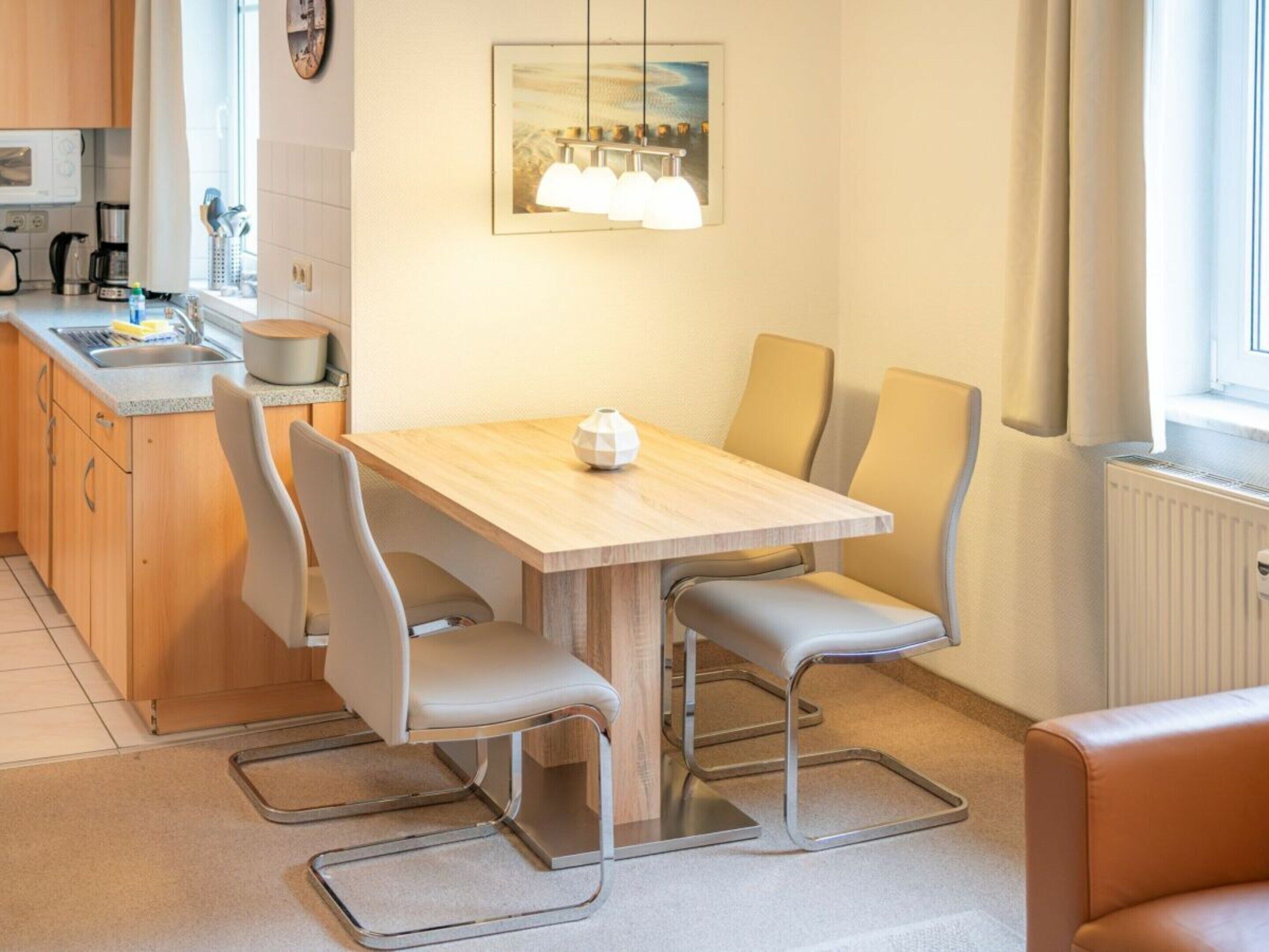 Eine moderne Küche mit einem Holztisch und vier Stühlen, einer Mikrowelle und einem Wasserkocher.