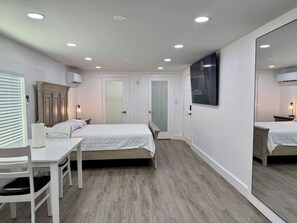 Ein Schlafzimmer mit Bett, Nachttisch, Stuhl und Spiegel.