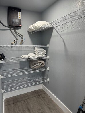 A walk-in closet with metal shelving units, a heating unit, and a mop. - Hale Haven - Luxury Stay in the Heart of Tampa! (Tampa)