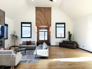A spacious living room with a high ceiling, large windows, and a modern fireplace. - Upscale Loft (Thunder Bay)