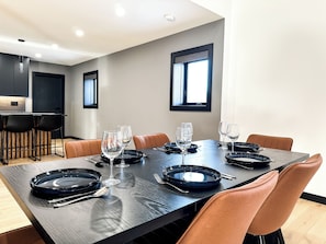 A modern dining area with a rectangular table set for six, surrounded by six chairs. - Upscale Loft (Thunder Bay)