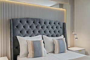 A modern bedroom with a tufted headboard, two bedside tables, and a nightstand. - Marvelous 5 bedroom home for vacation in Orlando with private pool (Davenport)