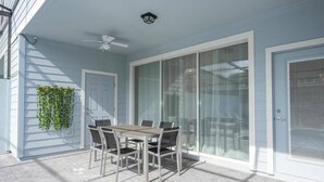 A covered patio with a table and chairs, a ceiling fan, and a sliding glass door.
