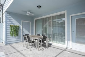 A covered patio with a table and chairs, a ceiling fan, and a sliding glass door.